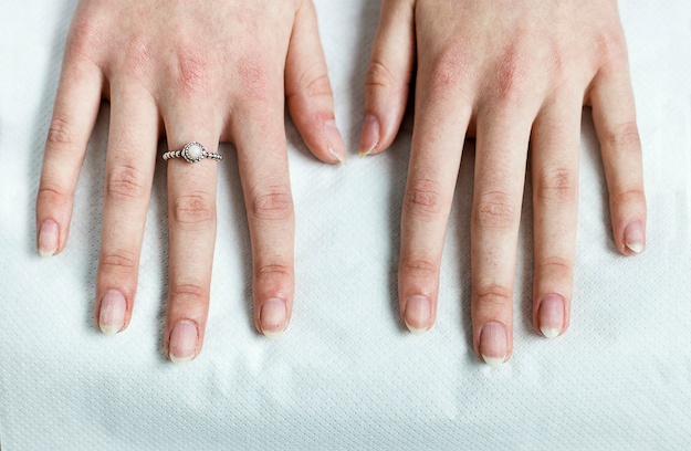 A woman holds her hands over paper towel after having her nails prepared for new nail polish in a beauty salon.