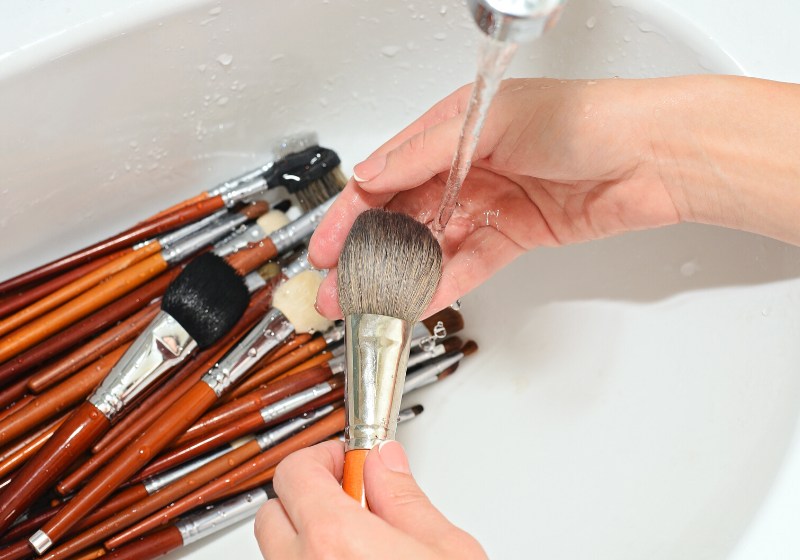 hands makeup artist washed brushes under | spring cleaning list