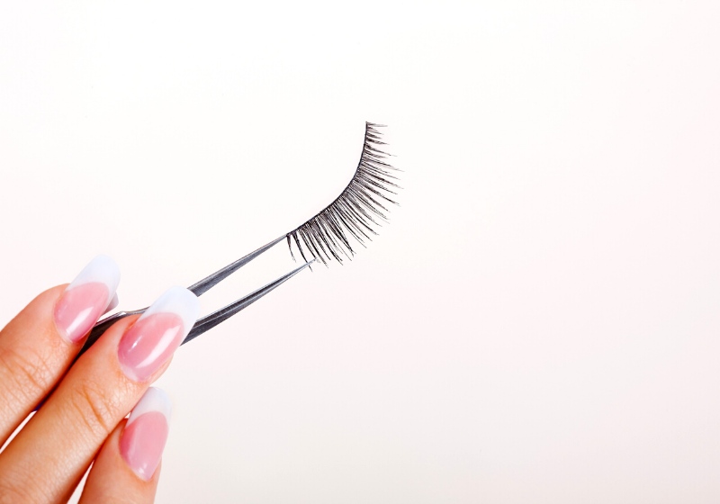 woman hand holding false eyelashes pincers | how to apply false eyelashes without glue