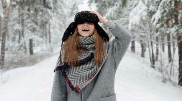 MADyRFjflJI-woman-in-grey-coat-holds-cap-and-stands-in-the-middle-of-snow-covered-ground | ways-to-wear-a-scarf | featured