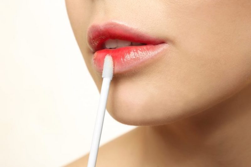 young-woman-applying-lip-gloss-closeup| makeup trends