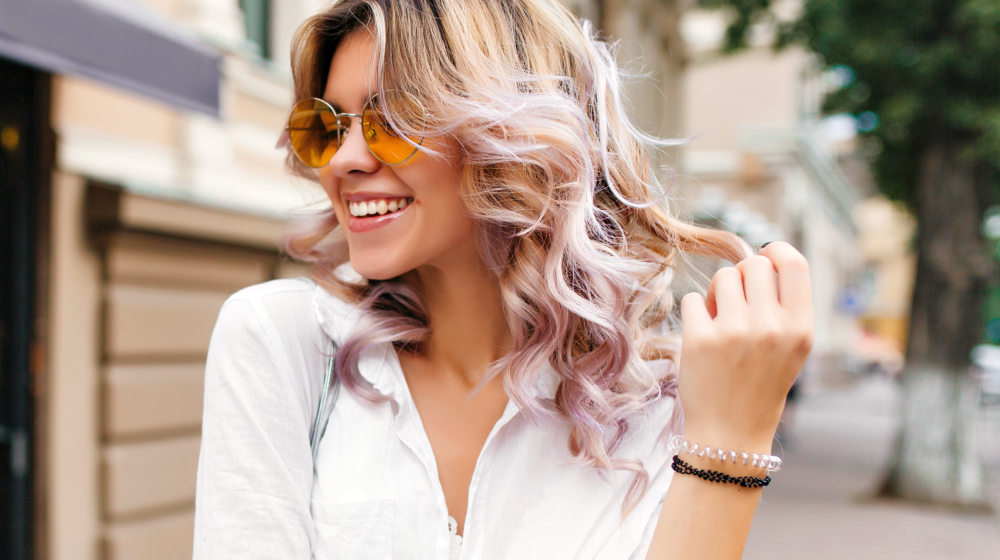 Pretty girl wearing sunglasses and bracelets playing with her short curly hair | How to Prevent Breakage | Hair Breakage FAQs | best hair brush to prevent breakage | Featured