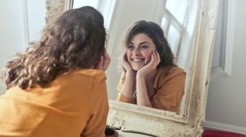 photo of woman looking in the mirror | Spring Skincare Routine: 9 Tips For A Healthier Skin This Spring | spring skincare | spring skincare trends | Featured