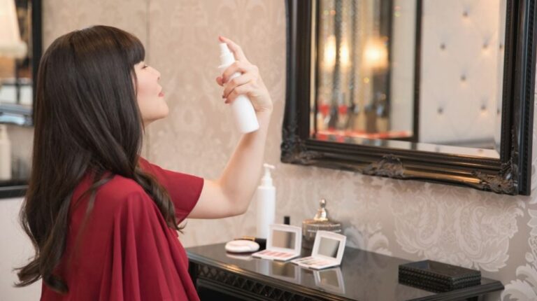 woman spritzing face mist in front mirror | Ran Out of Primer? Here's How To Make A DIY Primer Using Natural Ingredients | Featured