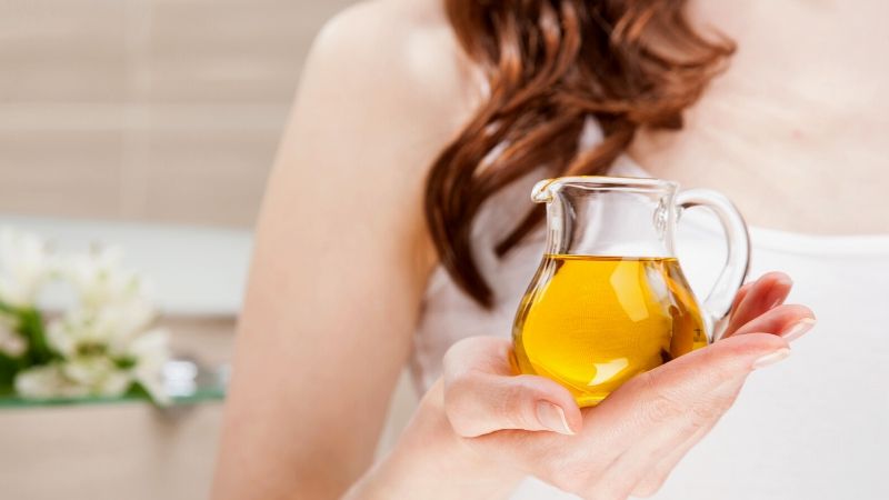 unrecognizable woman holding glass jug virgin olive oil | How To Tan Safely and Faster For A Glowing Sunkissed Skin