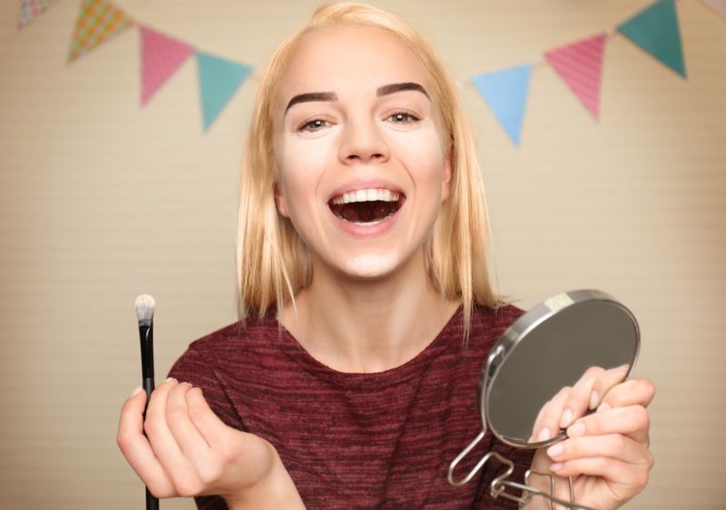beautiful-young-woman-applying-highlighter | Essential ## Face Brushes You Need In Your Makeup Arsenal | Best face brush