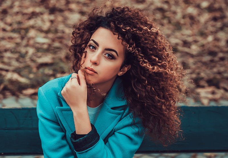 photo of woman sitting on park bench | how to take care of curly hair