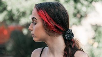 pensive woman with red hair strand | How To Create The Perfect Eyebrow Slit | Featured